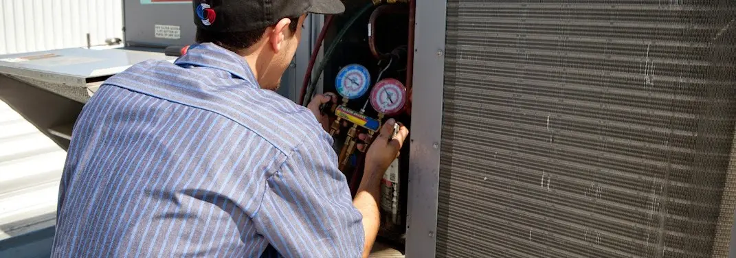 HVAC technician servicing a condenser unit in Cranston
